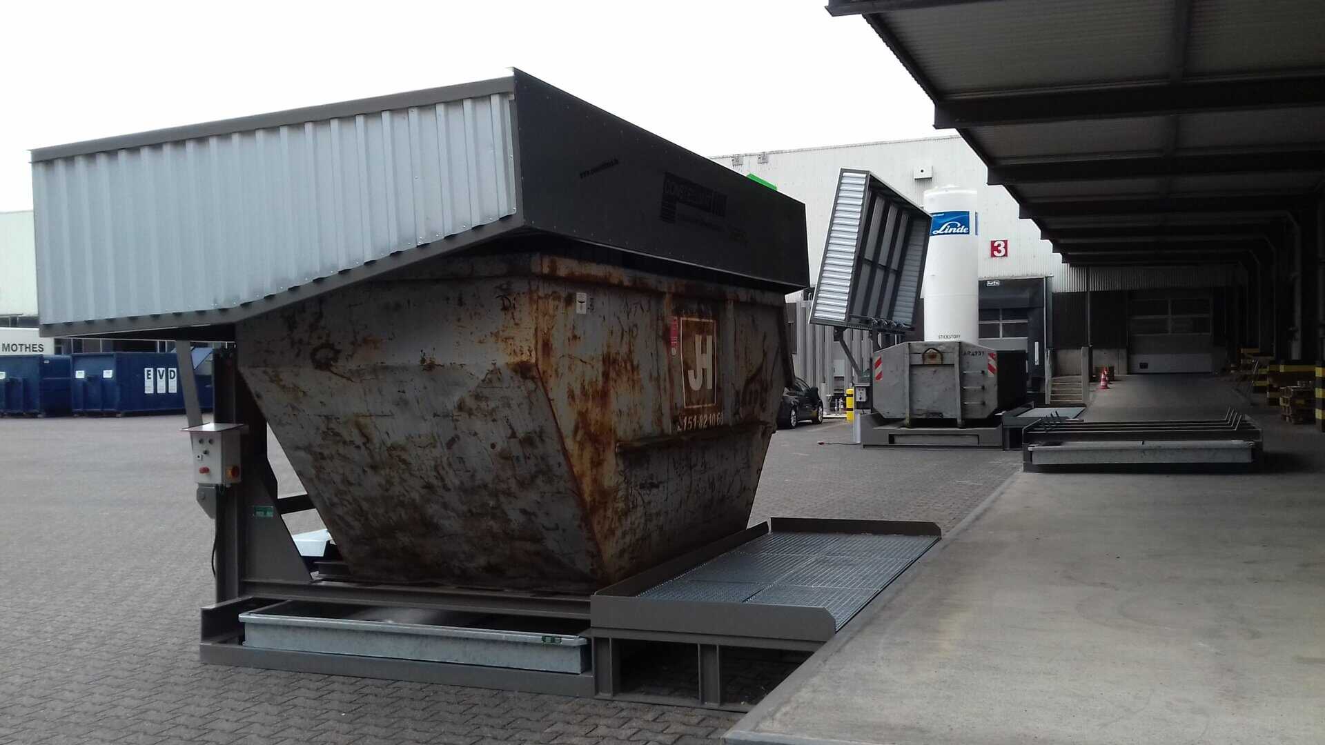 Schwerer, rostiger Containerstellplatz NCQ HS 100 für Abfallmanagement und Recycling. Im Hintergrund Containerstellplatz für Abrollcontainer.